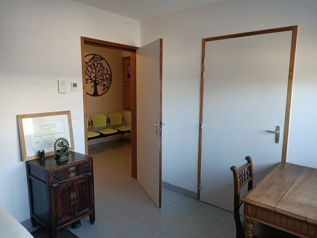 Salle de soin du cabinet DAO HE à Luzinay, avec la salle d’attente au fond